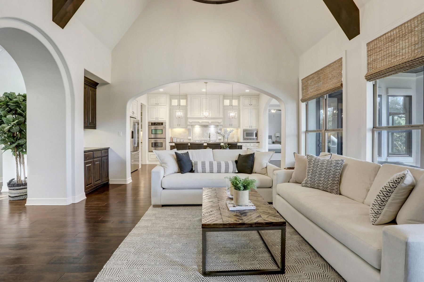 Vaulted living room with arched openings, cream sofas and a view into a white kitchen