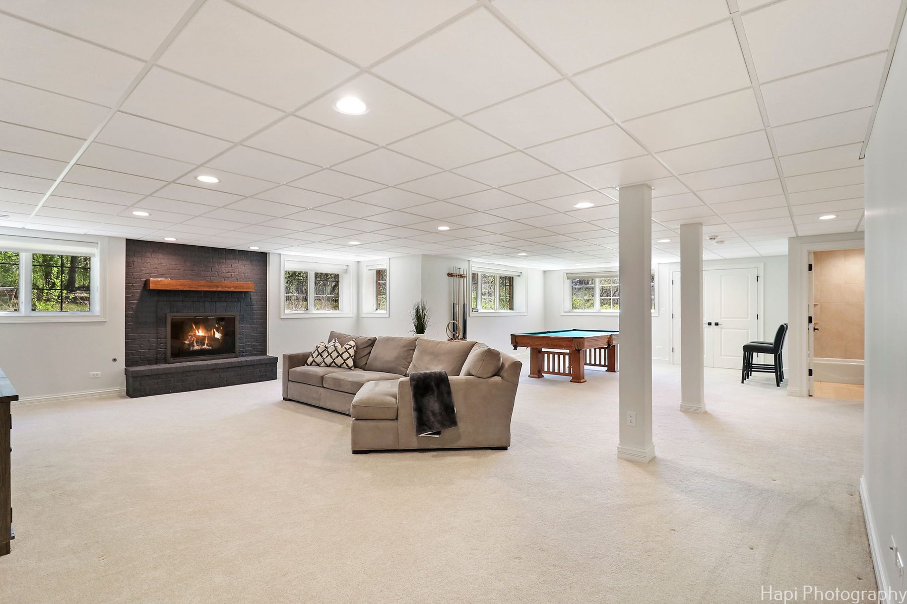 Vaulted family room with a stone fireplace, cream sectional and wrought-iron chandelier