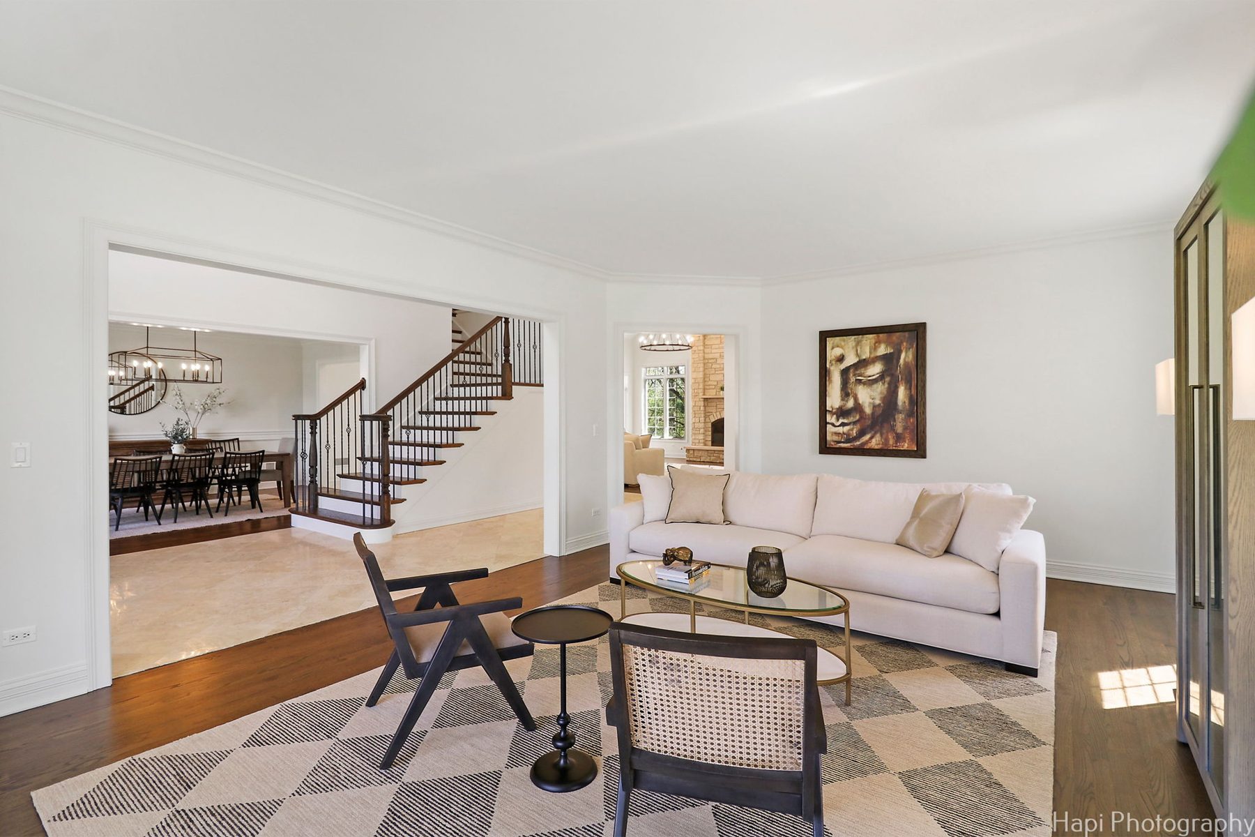 Living room with a linen sofa, cane-back chairs, a glass and brass coffee table and a diamond-pattern rug
