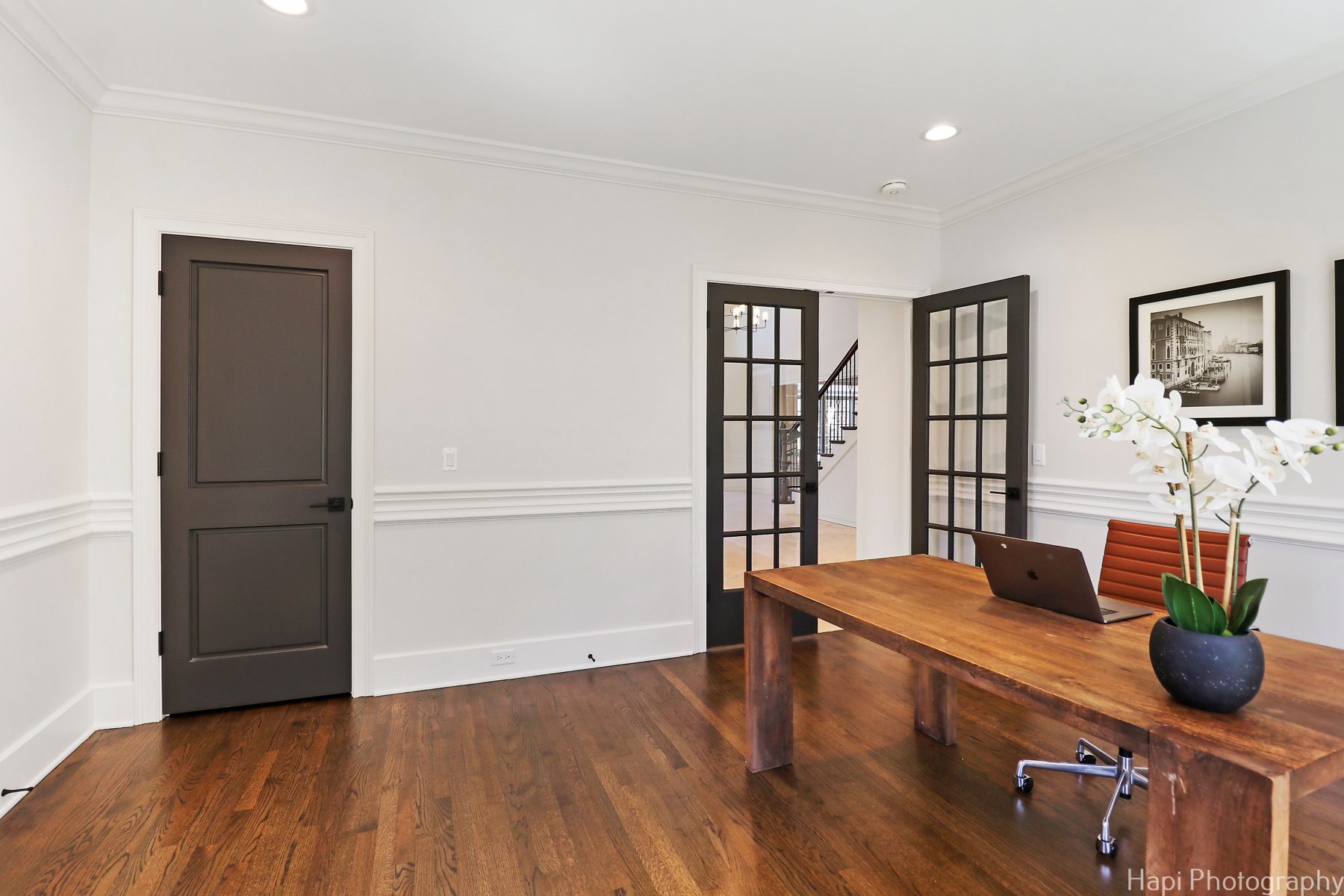 Home office with charcoal doors, chair rail molding and a reclaimed wood desk