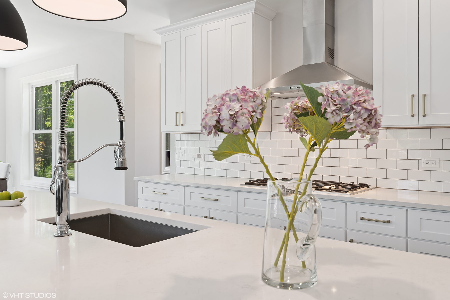 Close view of the quartz island, chrome spring faucet and white subway tile backsplash